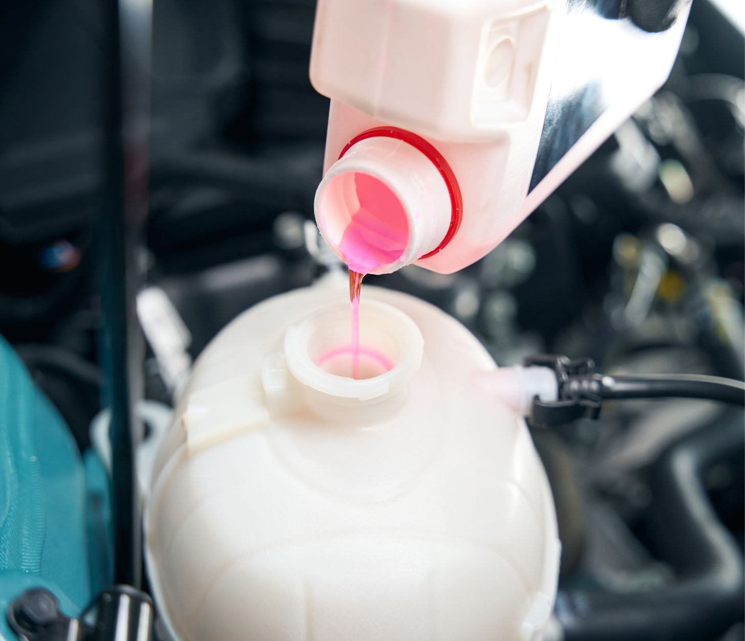 Roze koelvloeistof wordt bijgevuld in motorruimte van auto